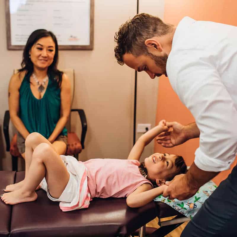 A girl child laying on bed and Dr. Sam checking her response for physical movement