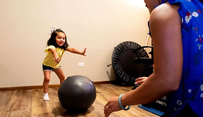 Dr. Lynn with a girl child playing with black ball