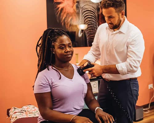 Dr. Sam giving a woman a shockwave therapy treatment for shoulder pain